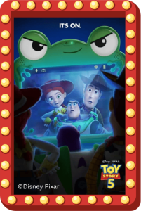 Toy Story 5 poster with glowing marquee bulbs; a playful green alien watches Woody, Buzz, and Jessie on-screen in a cinematic scene.